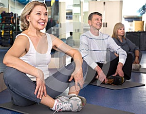 Men and women are engaged on mat in gym