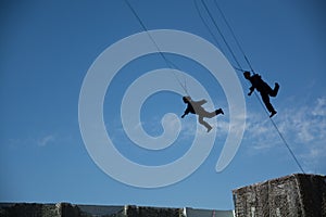 Men and women flying in sky with safety rope.