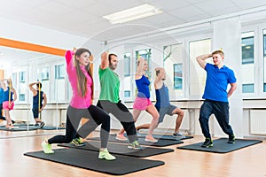 Men and women in gym doing pilates workout
