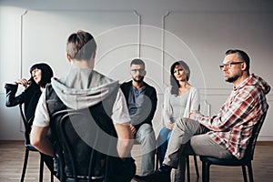 Men and women listening about teenager`s anxiety problems during group therapy