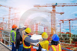 Men and woman meeting with Engineers and supervisors are standing reading the blueprints the construction site photo