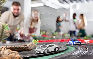 Men and women play with slot car racing track