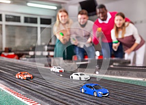 Men and women play with slot car racing track