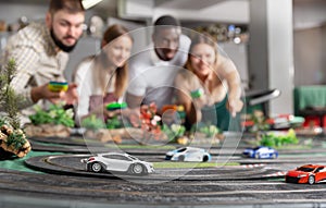 Men and women play with slot car racing track