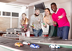 Men and women play with slot car racing track