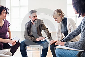 Men and women sitting in a circle during group therapy, supporting each other.