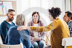 Men and women sitting in a circle during group therapy, supporting each other.