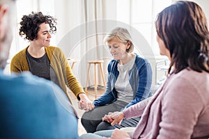 Men and women sitting in a circle during group therapy, supporting each other.