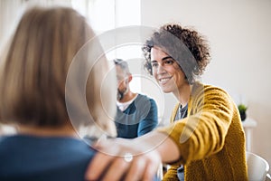 Men and women sitting in a circle during group therapy, supporting each other.