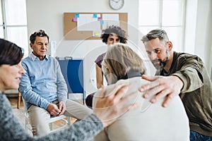 Men and women sitting in a circle during group therapy, supporting each other.