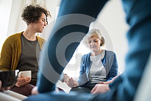 Men and women sitting in a circle during group therapy, supporting each other.