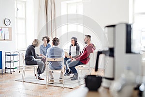 Men and women sitting in a circle during group therapy, talking.