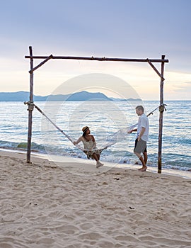Men and women watching sunset from a hammock on the beach in Pattaya Thailand Ban Amphur beach