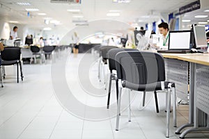 Men and women work at computers in car dealership office