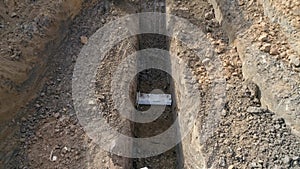 Men at work outdoor outside with heavy machinery loading arm installing water pipeline. Drone above excavating bulldozer