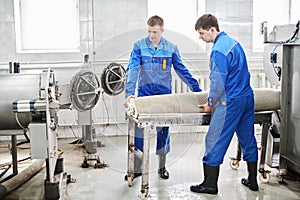 Men workers cleaning get carpet from an automatic washing machine and carry it in the clothes dryer