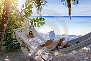 Men working on a tropical beach with his laptop