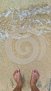 Mens feet, sand, and wave