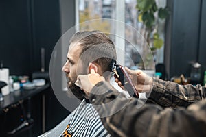 Master in barbershop makes men& x27;s haircutting with hair clipper