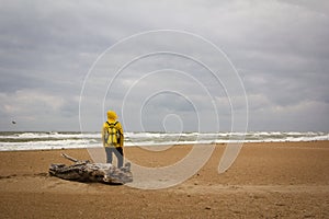 Men in yellow raincoat on the beach looking at storm.