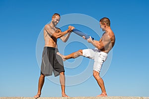 Men with yoga mat captured in motion blue sky background. Sportsman fighting. Practice fighting skills outdoor. Improve