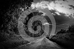 Menacing view of a rural dirt track lane showing storm clouds gathering.