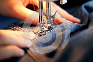 Mend jeans on a sewing machine. Patch torn jeans with a sewing machine. The concept of industrial production of handmade