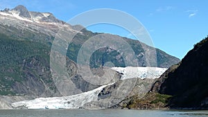 Mendenhall Glacier in Juneau Alaska. Large Glacier sliding into a lake with a waterfall beside it. Very popular tourist stop