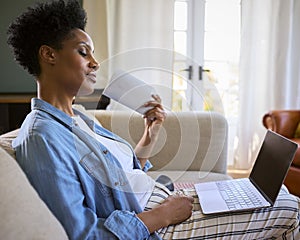 Menopausal Mature Woman At Home With Laptop Having Hot Flush Fanning Herself