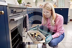 Menopausal Mature Woman With Poor Memory Burning Meal In Oven At Home