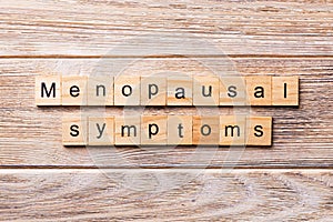 Menopausal symptoms word written on wood block. menopausal symptoms text on wooden table for your desing, concept