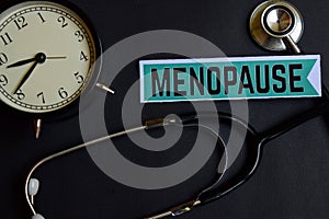 Menopause on the paper with Healthcare Concept Inspiration. alarm clock, Black stethoscope.