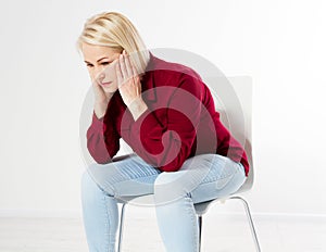 Menopause. Sad middle-aged woman with a headache sits on a chair, female head ache migraine