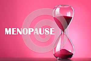 Menopause word and hourglass on pink background