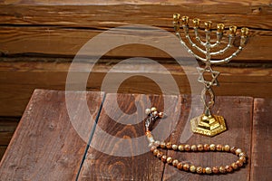 Menorah and beautiful rosary on a wooden table on a wooden wall