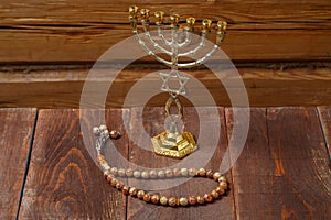 Menorah and beautiful rosary on a wooden table on a wooden wall.