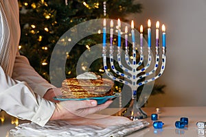 Menorah and potato latkes on Jewish holiday table during Hanukkah.