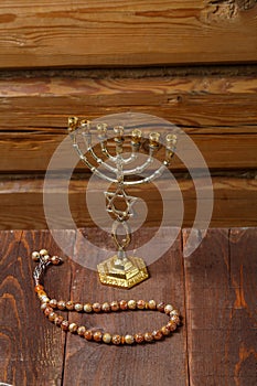 Menorah and rosary on a wooden table on a wooden wall