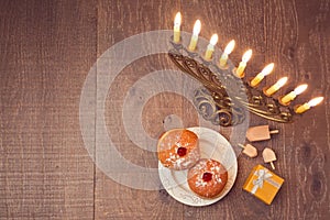 Menorah and sufganiyot on wooden table for Hanukkah celebration. View from above