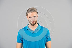 Mens beauty, fashion and style. Man in blue tshirt on grey background. Guy with bearded unshaven face. Macho with blond hair and s