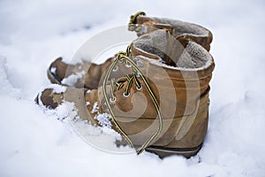 Mens brown boots in the snow, forgotten in the woods boots.