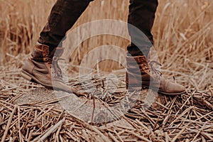 Mens brown shoes in rural territory. Unrecognizable masculine in trouses and boots. Leather old footwear. Walk outdoor