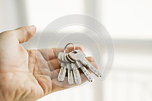 Mens hand holding a set of keys. Realtor is giving the keys to an apartment to clients. Focus on the keys. Bunch of keys