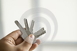 Mens hand holding a set of keys. Realtor is giving the keys to an apartment to clients. Focus on the keys. Bunch of keys