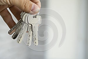 Mens hand holding a set of keys. Realtor is giving the keys to an apartment to clients. Focus on the keys. Bunch of keys