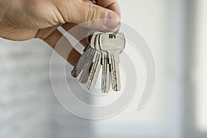 Mens hand holding a set of keys. Realtor is giving the keys to an apartment to clients. Focus on the keys. Bunch of keys