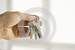 Mens hand holding a set of keys. Realtor is giving the keys to an apartment to clients. Focus on the keys. Bunch of keys