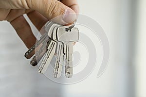 Mens hand holding a set of keys. Realtor is giving the keys to an apartment to clients. Focus on the keys. Bunch of keys