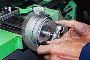 Mens hands on a cross feed handwheel of lathe machine