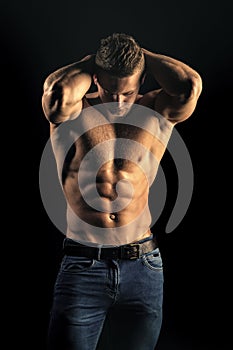 Mens heals body care. Man sportsman show muscular torso in jeans on black background